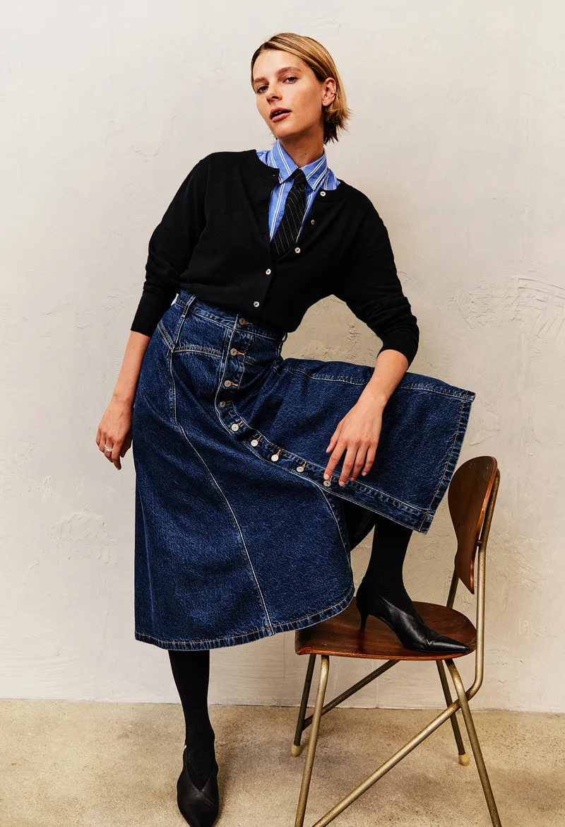 Person wearing a striped button up shirt, cardigan, and skirt