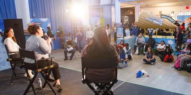 Three speakers sit on a stage at Ben & Jerry's Party for Protest Rights events. Audience members watch from below the stage.