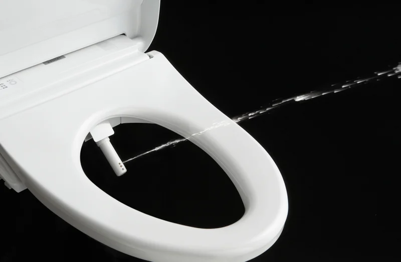 A TOTO WASHLET Bidet Seat is shown shooting a stream of water from its cleansing wand.