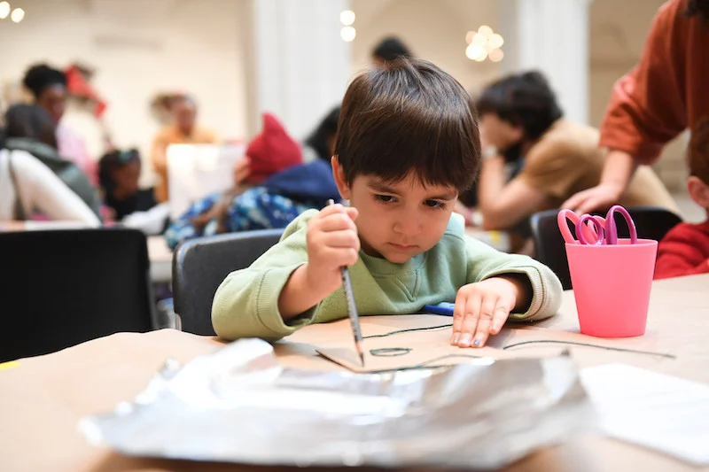A photograph of a child drawing with pencils