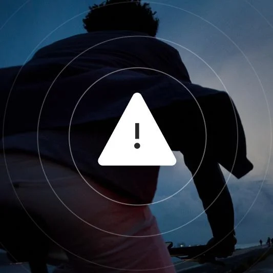 A graphic. A white warning triangle within concentric rings white resembling a radar screen. The background is a silhouetted figure on a bike against a dark sky.