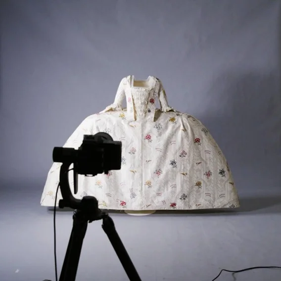 A historic garment mounted and displayed in front of a camera ready for photography.