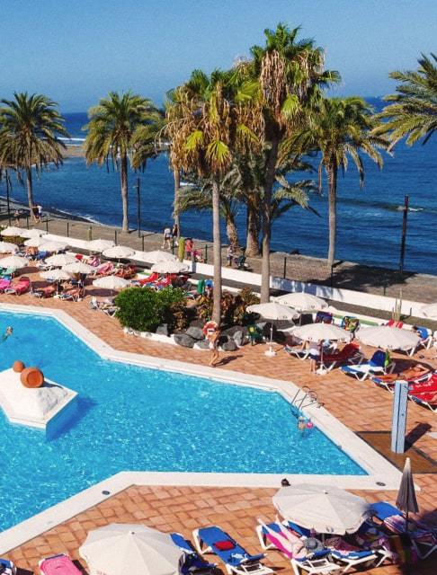 Image Description: A beachside pool surrounded by sun loungers and umbrellas
