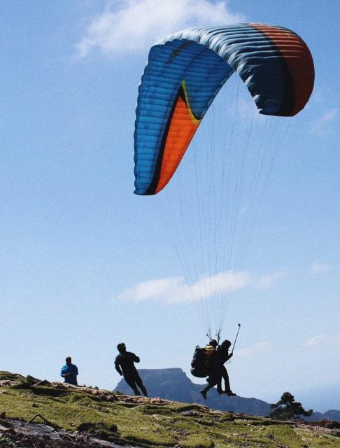 Image Description: Paragliders landing on a hill