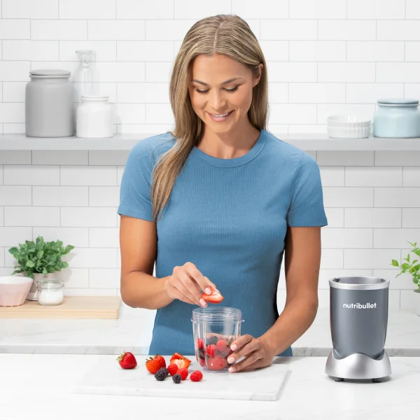 Woman introducing berries into a cup next to the nutribullet Pro