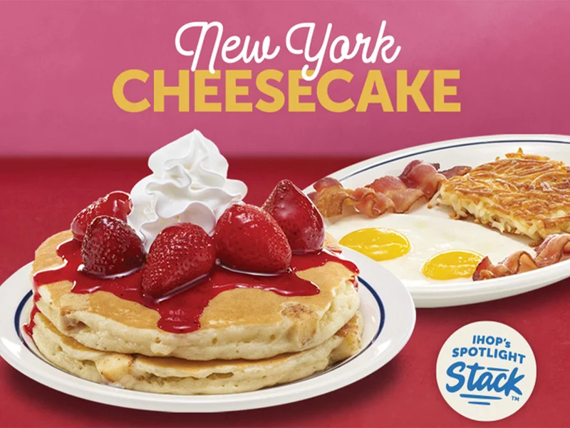 A  plate of New York Cheesecake pancakes beside a plate of sunny side up eggs, bacon, and hash browns.