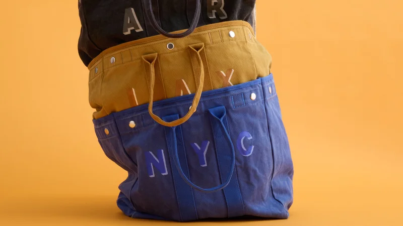 Custom-monogrammed Alex Mill tote bags stacked one on top of the other.