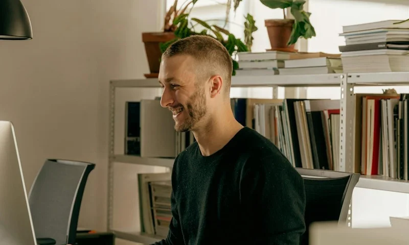 Man smiling looking at a computer monitor
