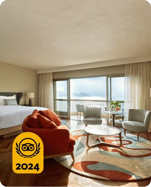 Image Description: A room with a red chair and a large balcony overlooking the water. A gold 2024 Travelers’ Choice Awards Best of the Best badge is on the bottom left corner of the image.
