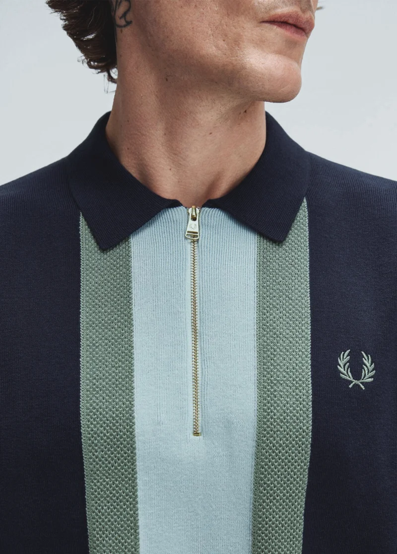 New Releases: a close up of a navy fine knitted quarter zip polo with duck-egg blue and sky blue panelling