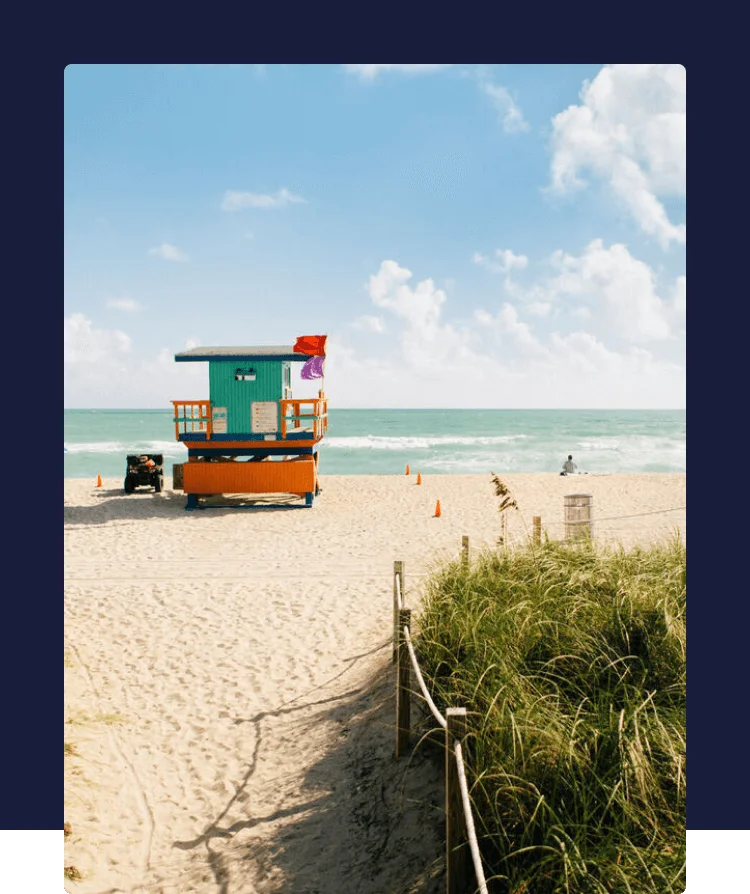 A lifeguard tower on a sandy beach with beach umbrellas