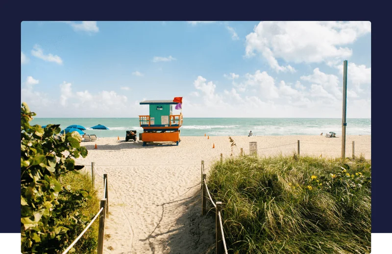 A lifeguard tower on a sandy beach with beach umbrellas
