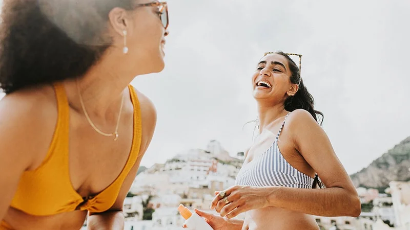 Image description: Two friends laughing together on the beach