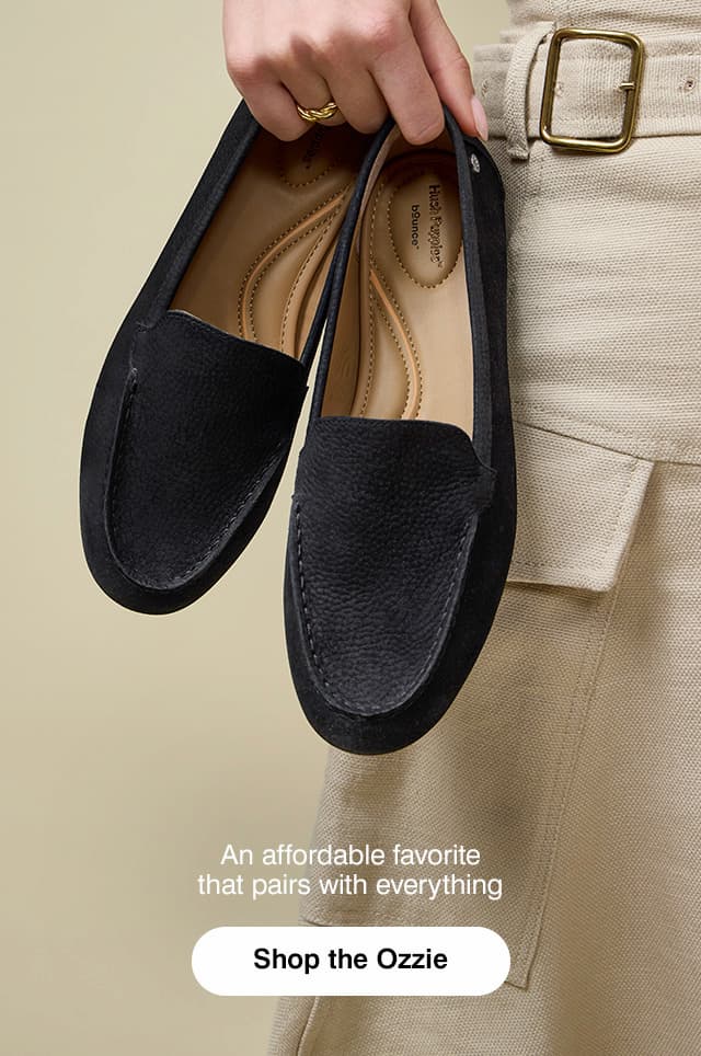 A woman in a belted neutral dress holding a pair of the Ozzie Loafers in Black suede. The text says An affordable favorite that pairs with everything. Shop the Ozzie