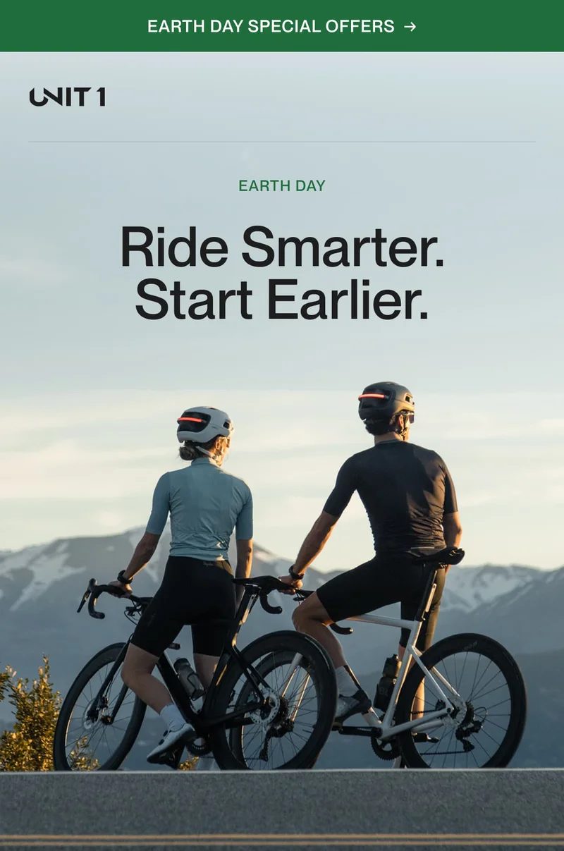 Two cyclists wearing UNIT 1 smart helmets with integrated lights pause at sunrise on a scenic mountain road, promoting safe and sustainable riding for Earth Day.
