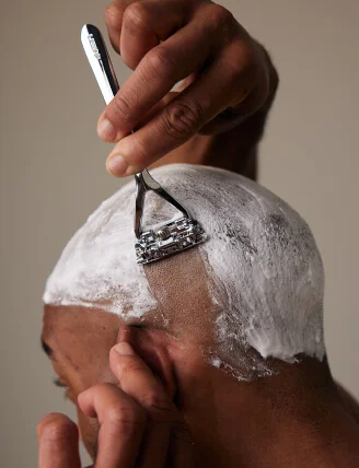 man shaving his head with chrome leaf razor