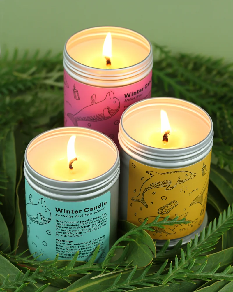 Three candles are clustered in a bed of plants