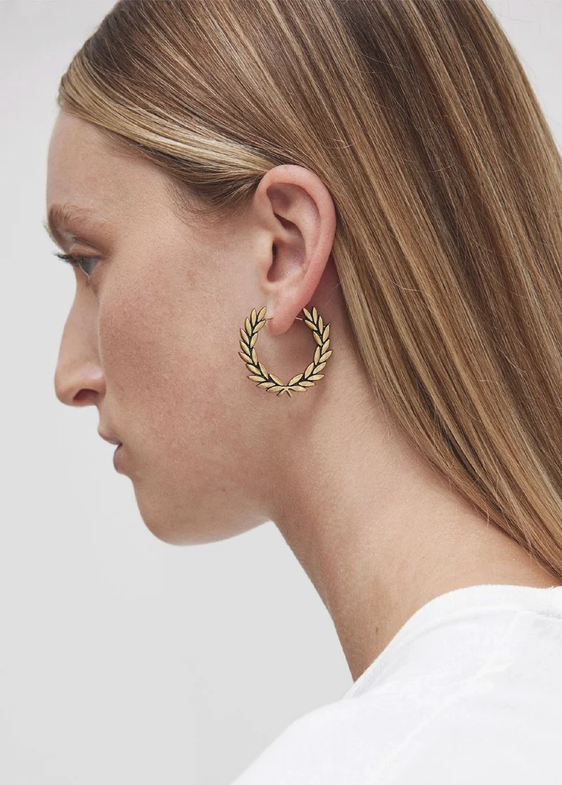 Woman wearing gold laurel wreath earrings