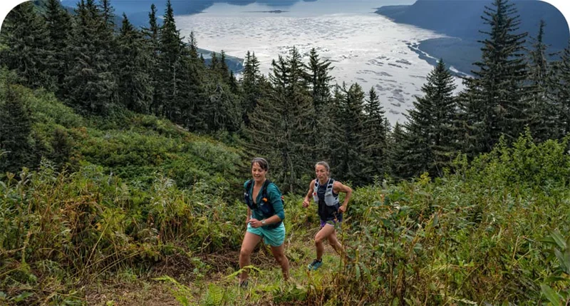 Two people running on a trail through trees.