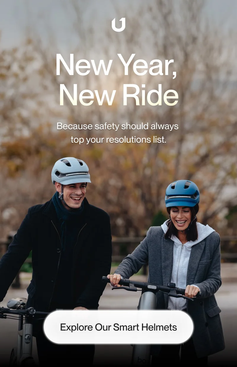 Two smiling cyclists wearing UNIT 1 smart helmets while riding together. Make safety a priority in your New Year’s resolutions.