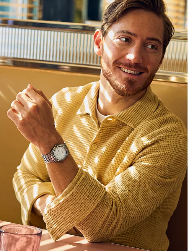 A man seated at a table, wearing AW0130-85A.