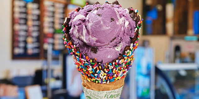 Waffle cone with UltraViolet ice cream in a Scoop Shop setting.