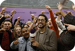 A
group of people cheering in front of a Festival step and repeat.