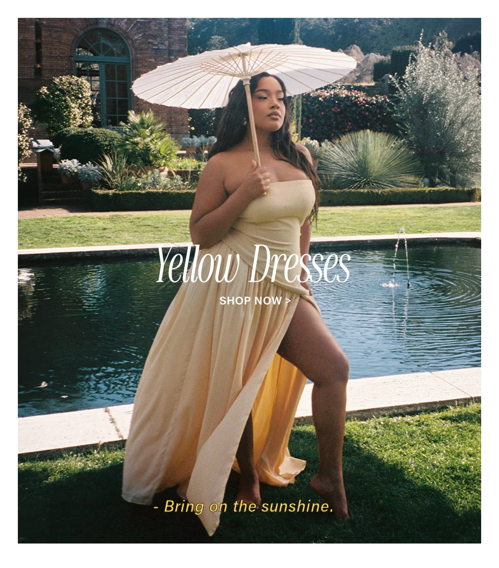 Stylish woman in a flowing yellow strapless maxi dress with a white parasol, promoting the vibrant new collection of yellow dresses. Shop now!