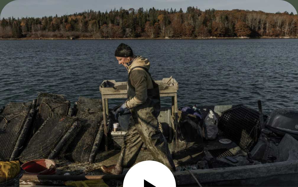 A person in dirty slickers walks on their small boat.