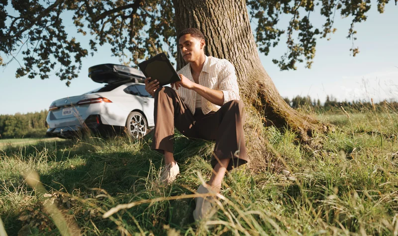 Man reading by tree, BMW parked behind him