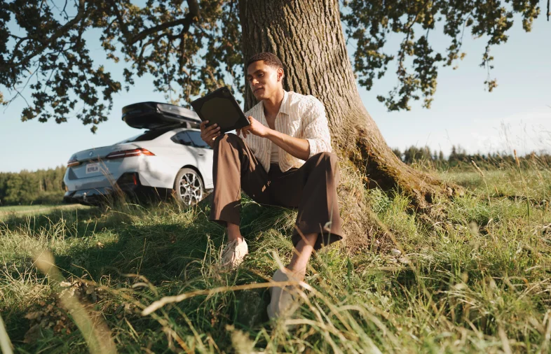 Man reading by tree, BMW parked behind him