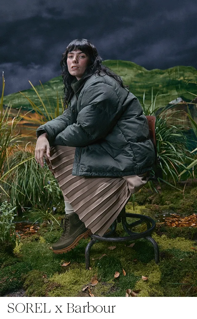 A woman wearing rugged boots and sneakers with a puffer jacket and pleated skirt.