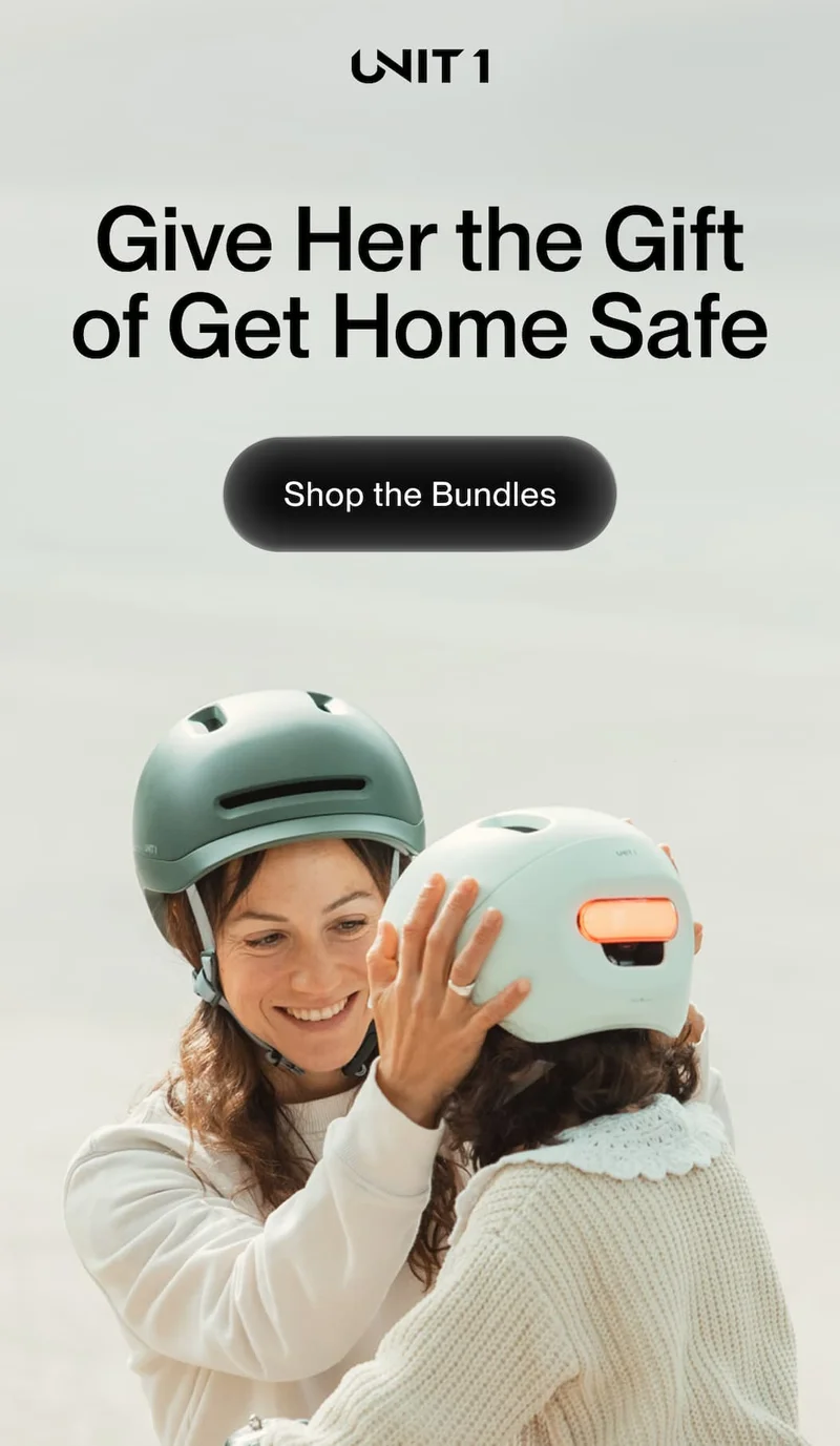 Mother helping child wear UNIT 1 smart helmet with rear safety light for visibility and protection