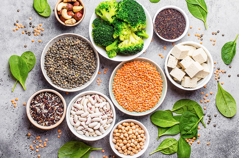A colorful flat lay of high-protein, eco-friendly foods including lentils, tofu, beans, chickpeas, and broccoli, promoting sustainable eating.