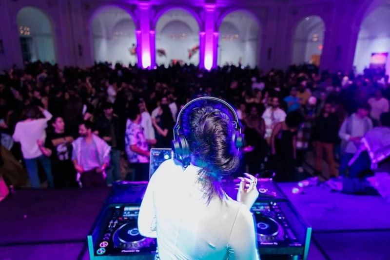 A DJ overlooks a crowded dance floor