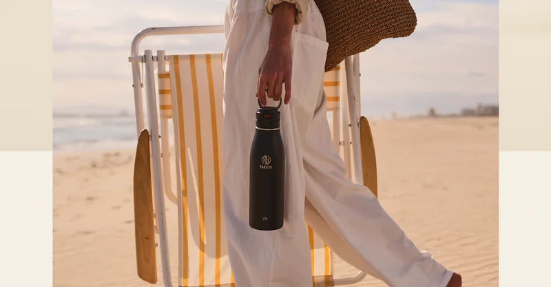 Black Takeya Traveler carried by the loop handle during a beach walk.