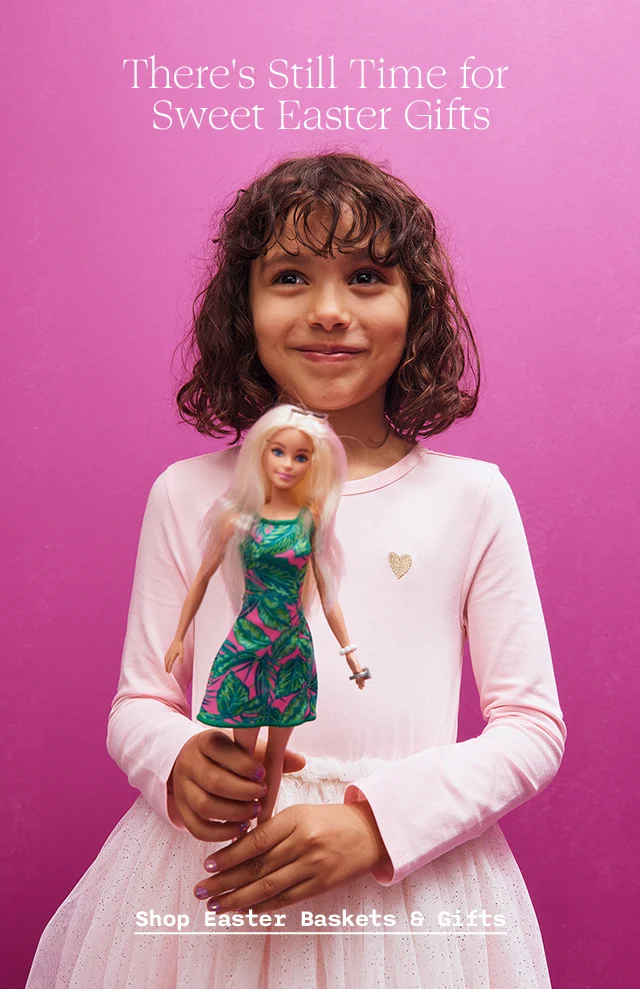 A girl in a dress holding a Barbie doll.