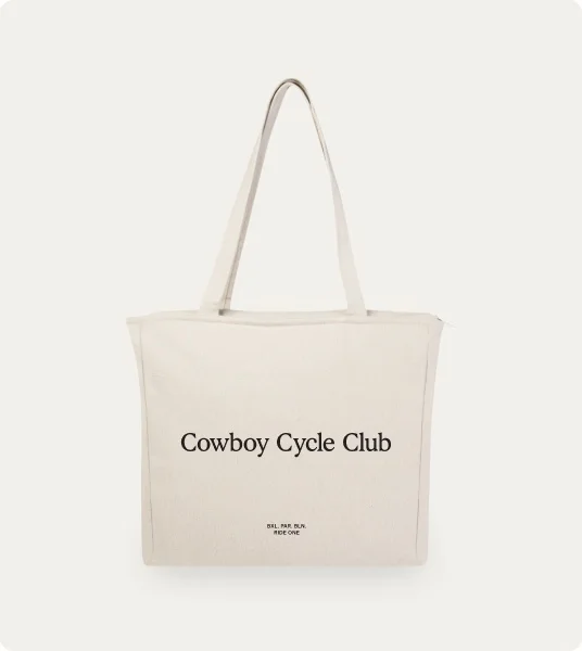 A photograph. A canvas tote bag, the text printed on the front reads "Cowboy Cycle Club"