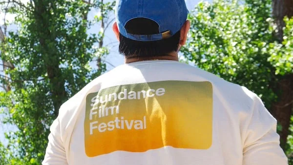 Male model facing away from the camera wearing the Summer Festival Merch tee and hat.