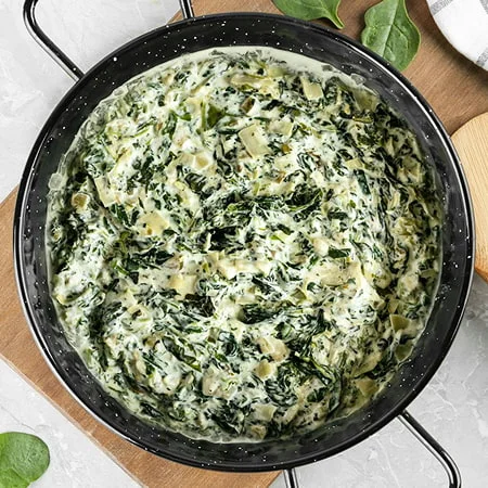 Warm spinach artichoke dip in a pan, featured as a nourish by nutribullet party snack.
