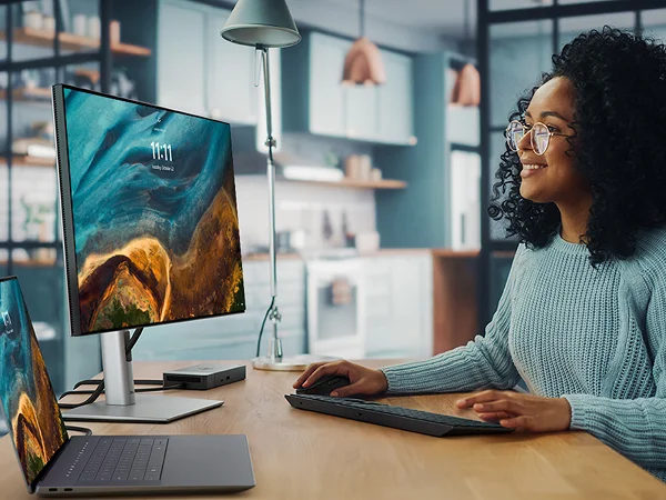 A Graphic Designer working on a Dell 16 Premium Laptop with a WD22TB4 docking station, 24 Ultrasharp Monitor, Pro Premium Collaboration Keyboard and Mouse.