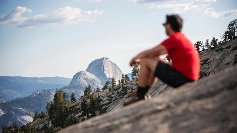 Image description: Hiker admiring Half Dome in Yosemite.
