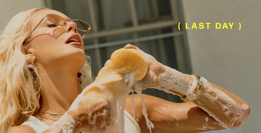 Blonde woman in sunglasses washing with a soapy sponge. LAST DAY promotion.