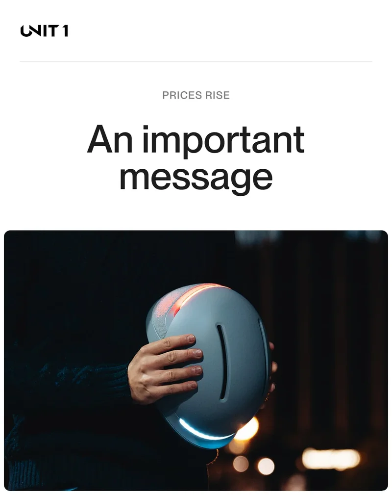 A person holding a UNIT 1 helmet at night, illuminated by its front and rear lights. The text above reads: "PRICES RISE - An important message."