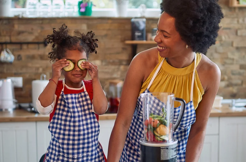 Woman and child at kitchen counter preparing a smoothie.