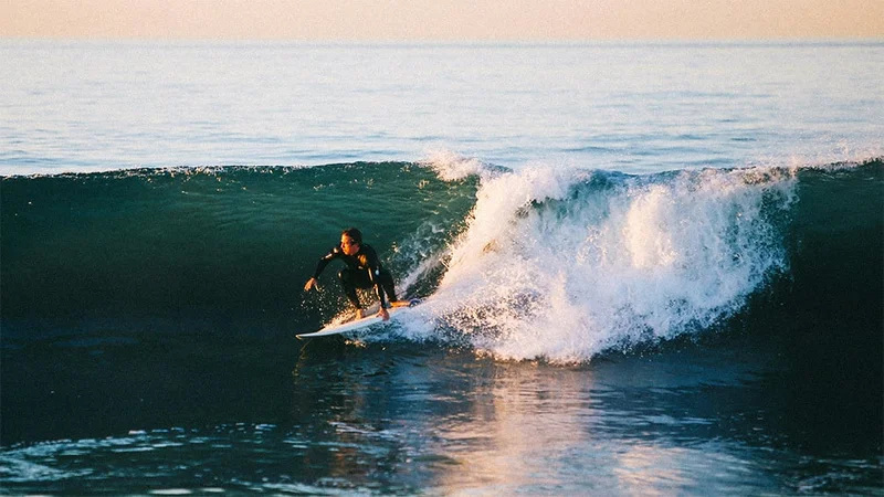 Image description: Man surfing in California at sunset.