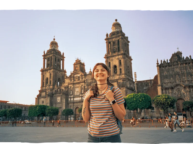 Image Description: A female traveler smiles for the camera in front of the Mexico City Metropolitan Cathedral