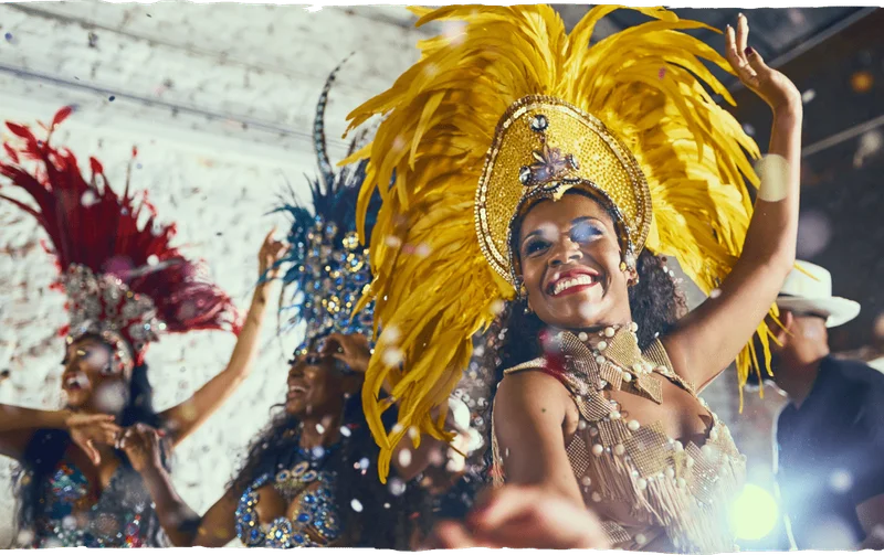 Image Description: A woman in an extravagant yellow headdress and costume dancing at the Rio Carnival
