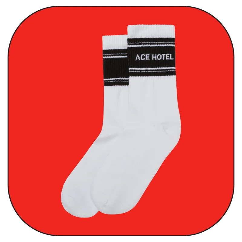 White socks with black stripes, featuring "ACE HOTEL" in black text within the stripes.