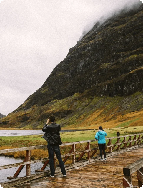Image Description: Travelers snapping photos of a volcanic mountain in Lochaber Geopark in Glencoe, the Scottish Highlands